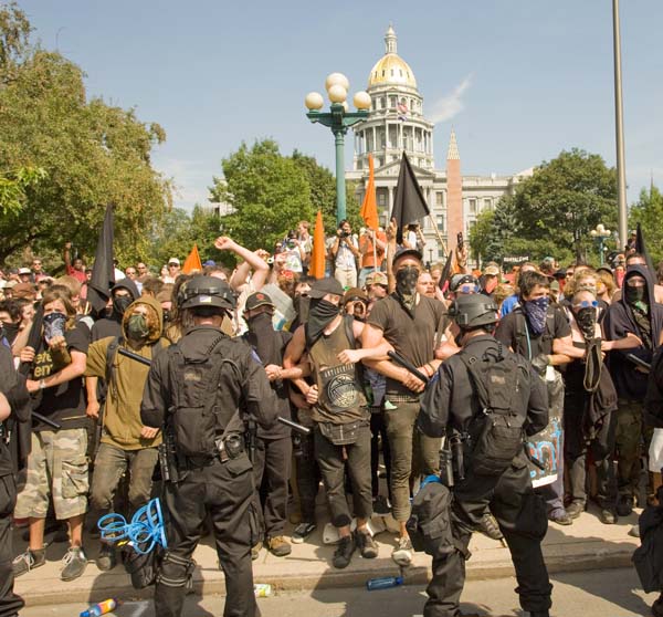 Protesters chanted “This is what a police state looks like! This is what a police state looks like!” and did everything verbally possible to insult and provoke the police in a hysterical manner. They screamed: “You cowards! You wouldn’t ever come here without those guns! You’re not men, you’re dirty machines.” I saw an open bottle full of liquid thrown out of the mob at police; wasn’t close enough to verify that it was filled with urine, but that’s what had been threatened.